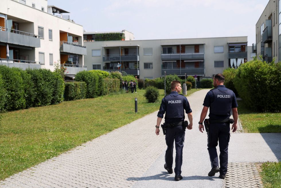 Police officers walk towards the flat of suspect Artur A following his deadly shooting