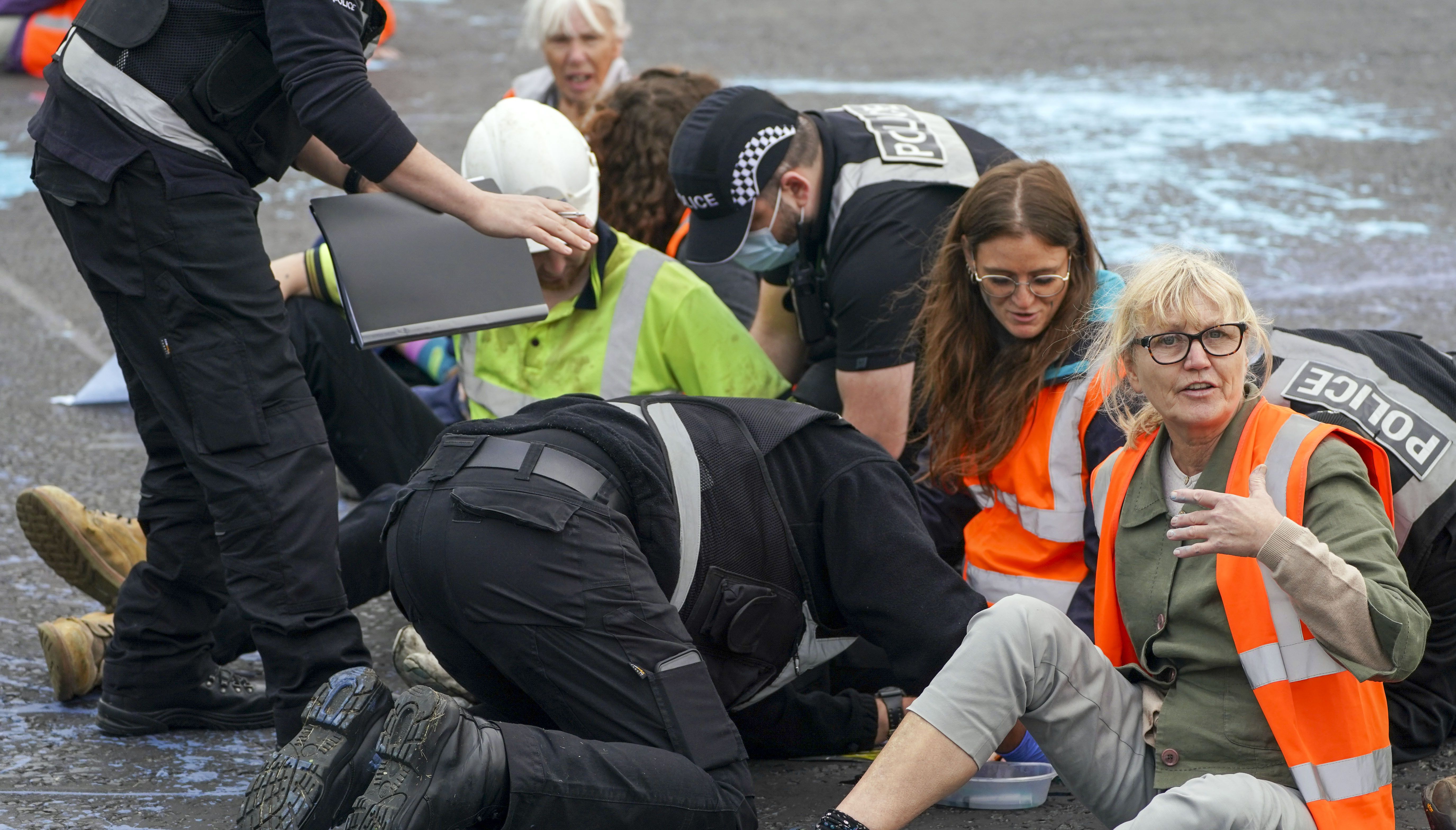 Police officers work to free protesters who had glued themselves to a slip road at Junction 4 of the A1(M), near Hatfield.