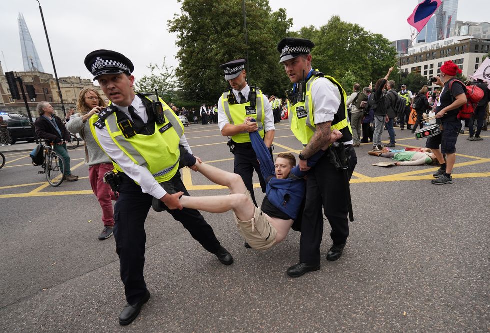 Police remove a man as members of Extinction Rebellion reach Tower Hill during their march in central London. Picture date: Monday August 30, 2021.