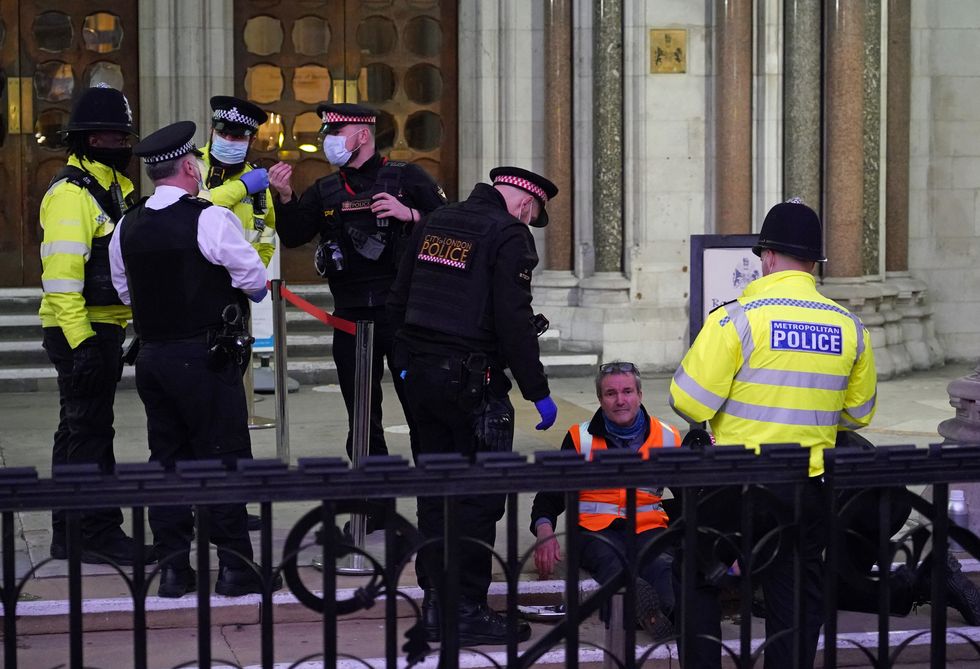 Police remove glue from Insulate Britain defendant Steve Pritchard, 62, who along with Theresa Norton, 63, Dr Diana Warner, 62, and El Litten, 35 , sat outside the Royal Courts of Justice in London, as they decided not to return to the afternoon session of their committal hearing. Picture date: Tuesday February 1, 2022.