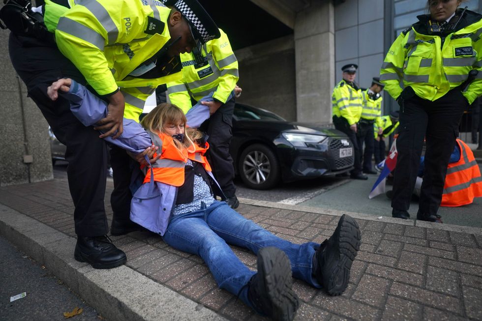 Police removing Insulate Britain protesters after they blocked a road near Canary Wharf in east London.