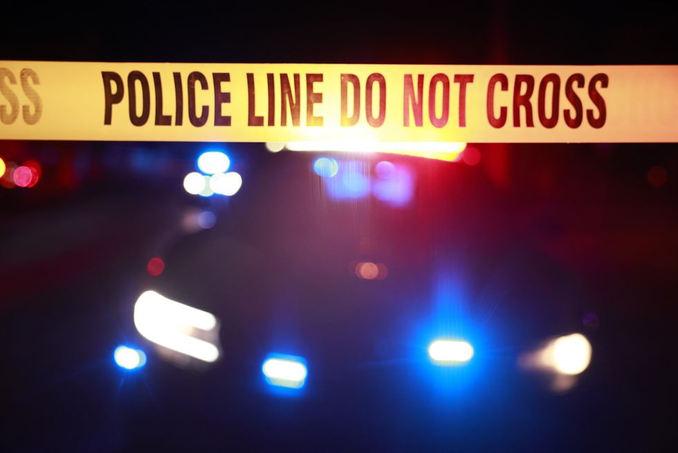 Police tape secures a crime scene with a police cruiser parked with flashing lights during an investigation at a residence