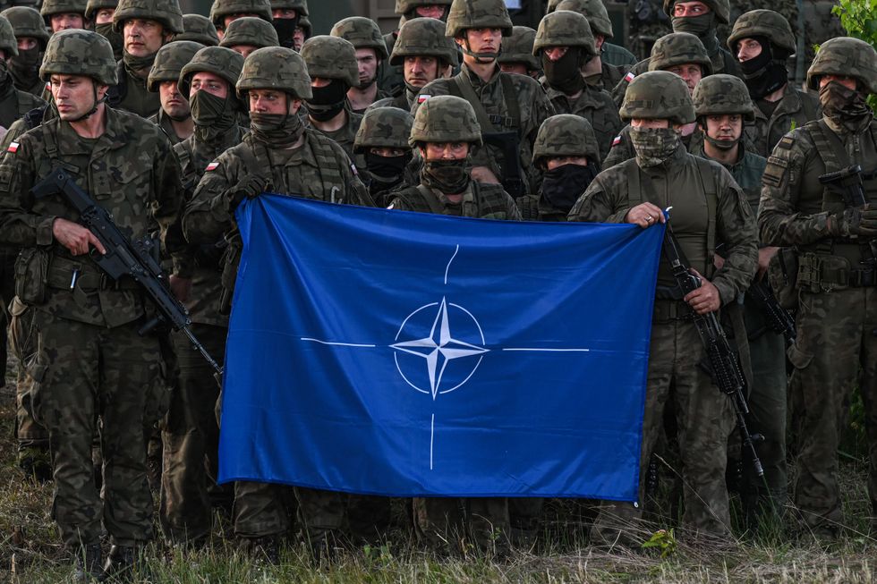 Polish soldiers hold a Nato flag