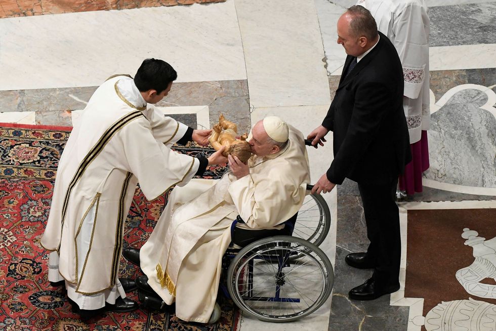 Pope Francis kisses a statue of baby Jesus as he celebrates Christmas Eve Holy Mass in St. Peter's Basilica at the Vatican, December 24, 2022. Vatican Media/\u00adHandout via REUTERS ATTENTION EDITORS - THIS IMAGE WAS PROVIDED BY A THIRD PARTY.
