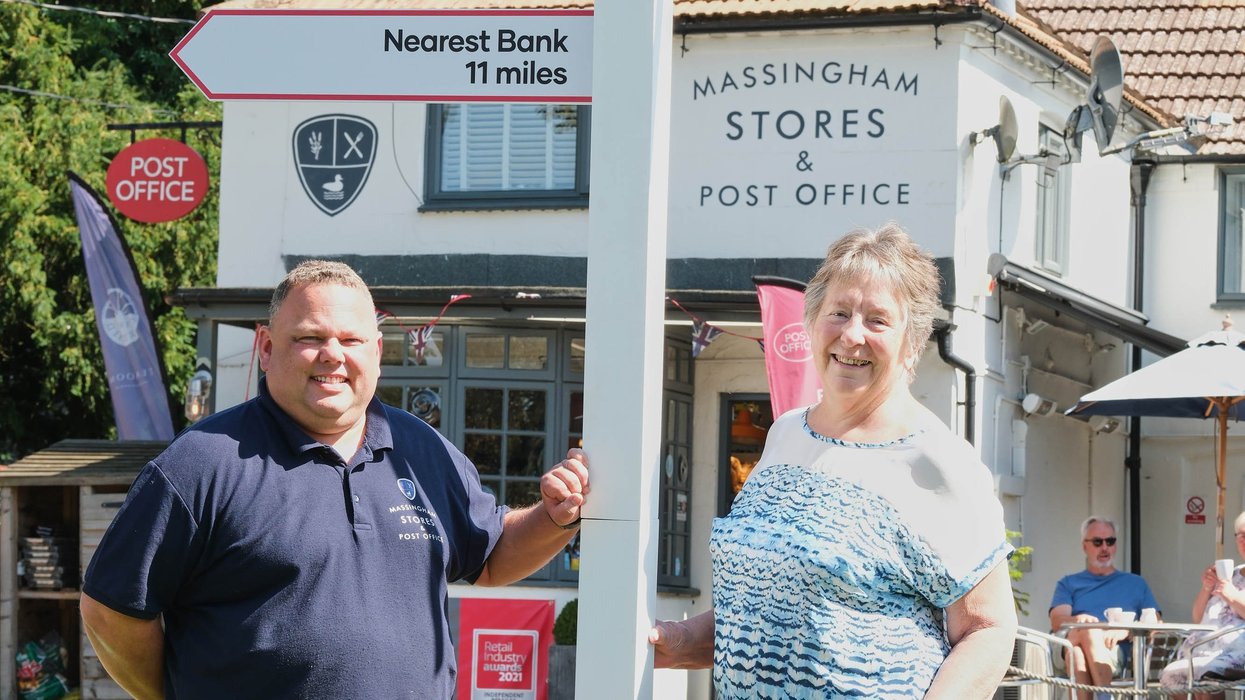 Post Office postmaster and Great Massingham resident Eddie Evans by sign pointing to nearest bank branches