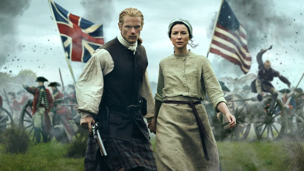 poster for outlander series with two characters walking in front of british and american flags