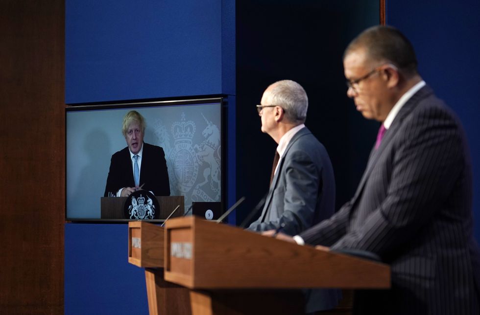 Prime Minister Boris Johnson appears on a screen from Chequers, the country house of the serving UK Prime Minister, where he is self-isolating, chief scientific adviser Sir Patrick Vallance and deputy chief medical officer for England Professor Jonathan Van Tam, during a media briefing in Downing Street