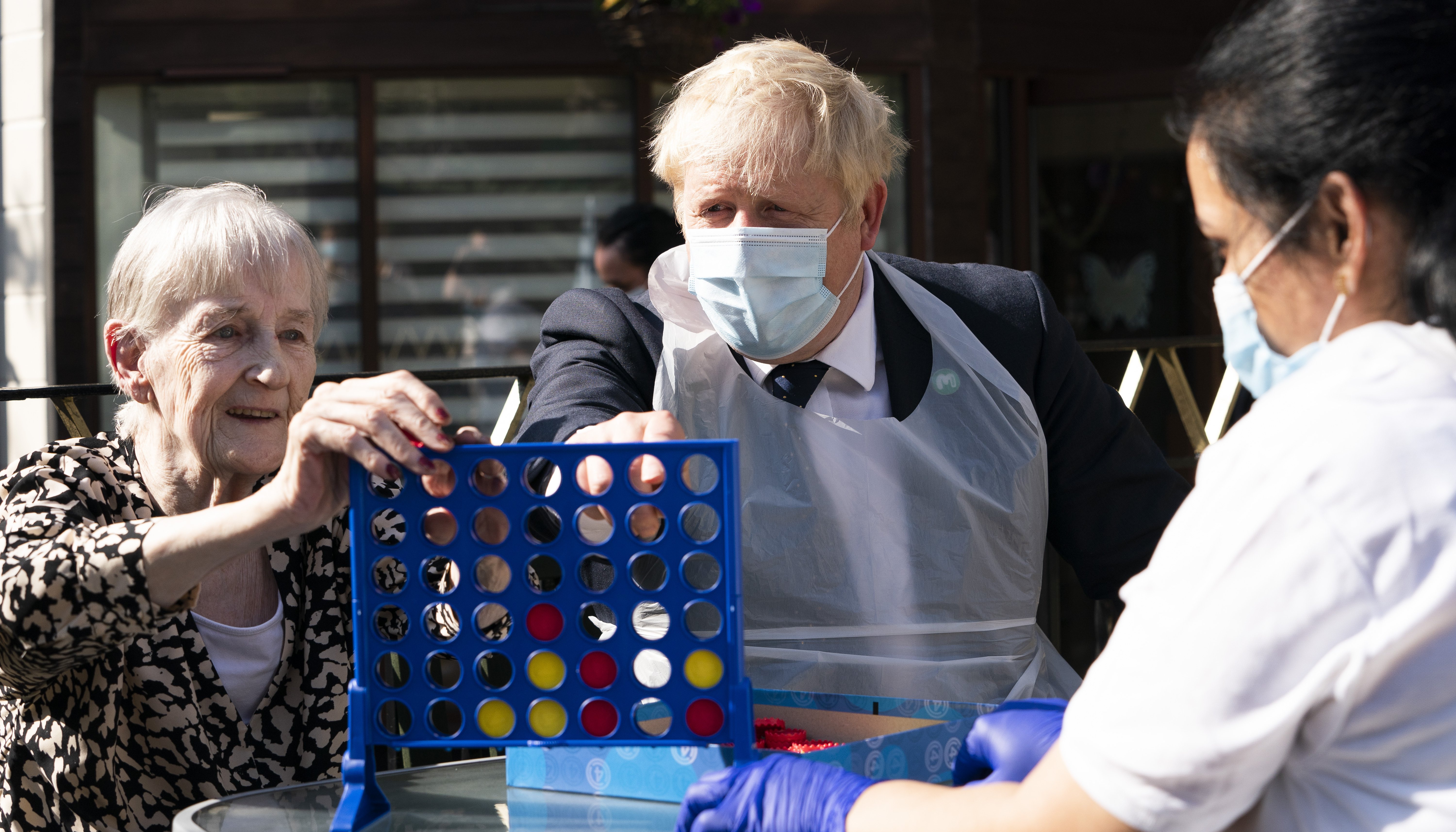Prime Minister Boris Johnson plays Connect 4 with resident Janet (left) and carer Lakshmi during a visit to Westport Care Home in Stepney Green, east London.