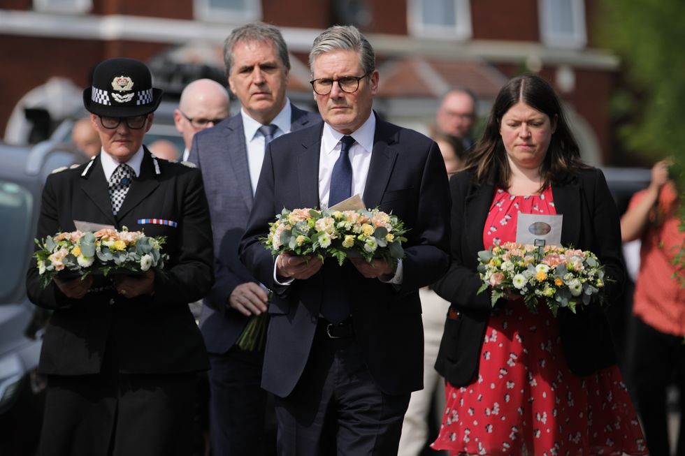 Prime Minister Keir Starmer (centre) is seen carrying a floral tribute near the scene in Hart Street, Southport,