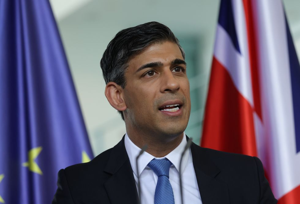 Prime Minister Rishi Sunak speaks to the media as he stands between the European Union and British flags