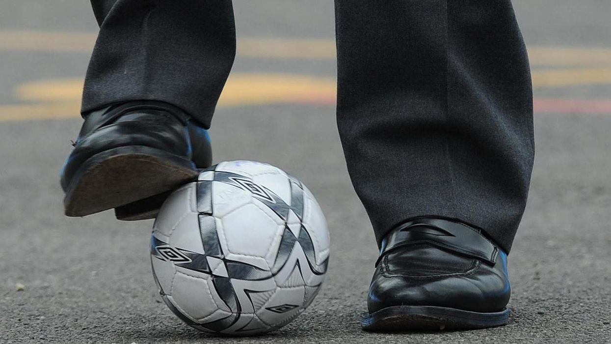 Prince William kicks a football during a trip to a school