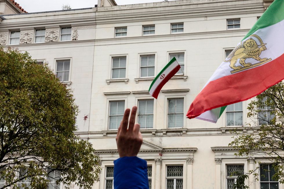Pro-democracy Iranian shows a victory sign against Islamic Republic of Iran national flag