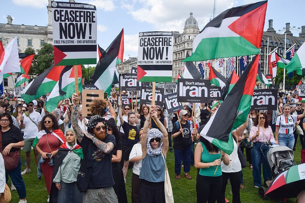 Pro-Palestine protesters hold up signs stating 'don't attack Iran'