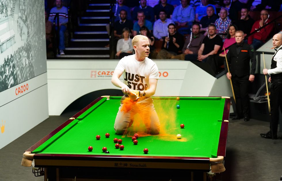 Protester releasing orange powder over snooker table