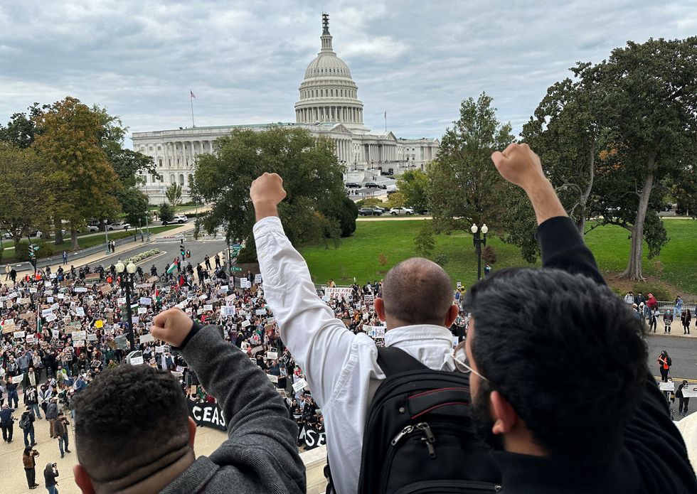 Protesters calling for a cease fire in Gaza and an end to the Israel-Hamas conflict demonstrate atop the steps of the Cannon House office building