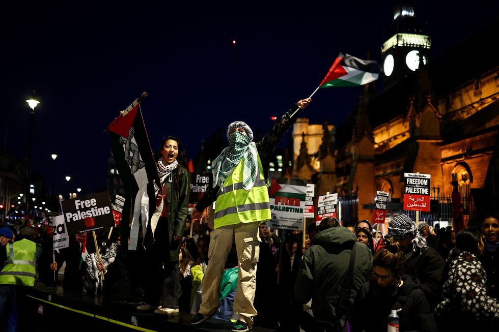 Protesters hold placards and flags as they chant slogans during a rally in support of Palestinians