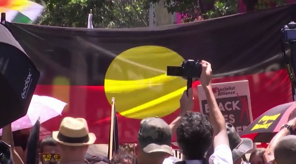 Protesters holding the Indigenous flag of Australia