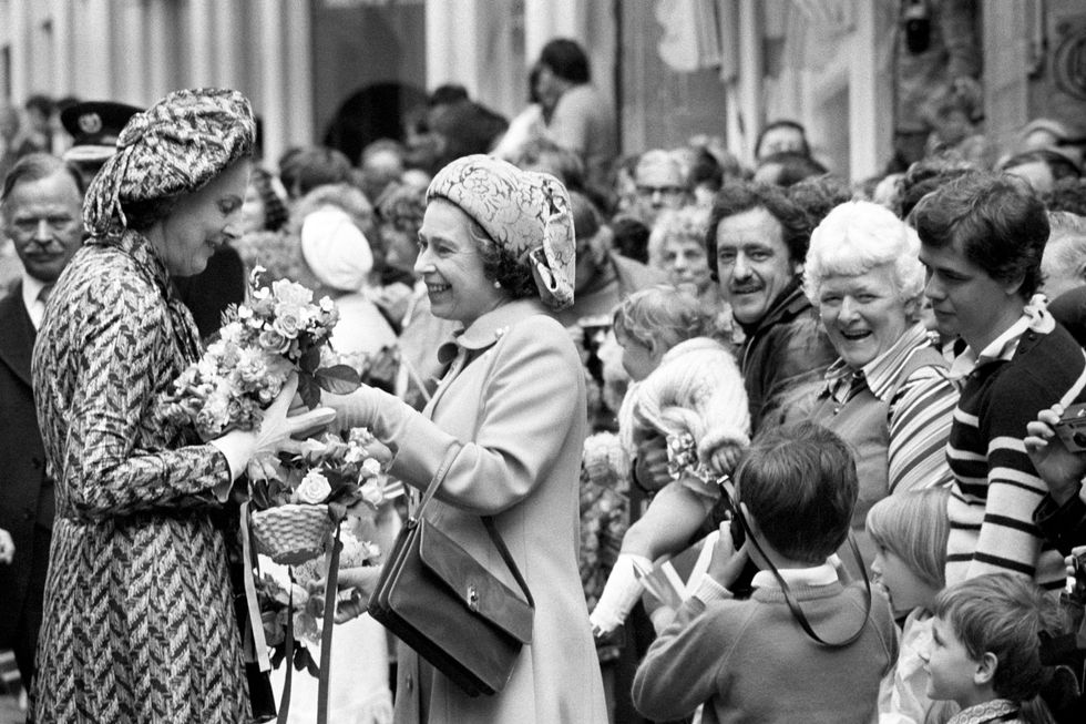 Queen Elizabeth II hands posies to her Lady in Waiting, the Duchess of Grafton, on a walkabout in St Peter Port, during her visit to the island of Guernsey, Channel Islands, in 1978.