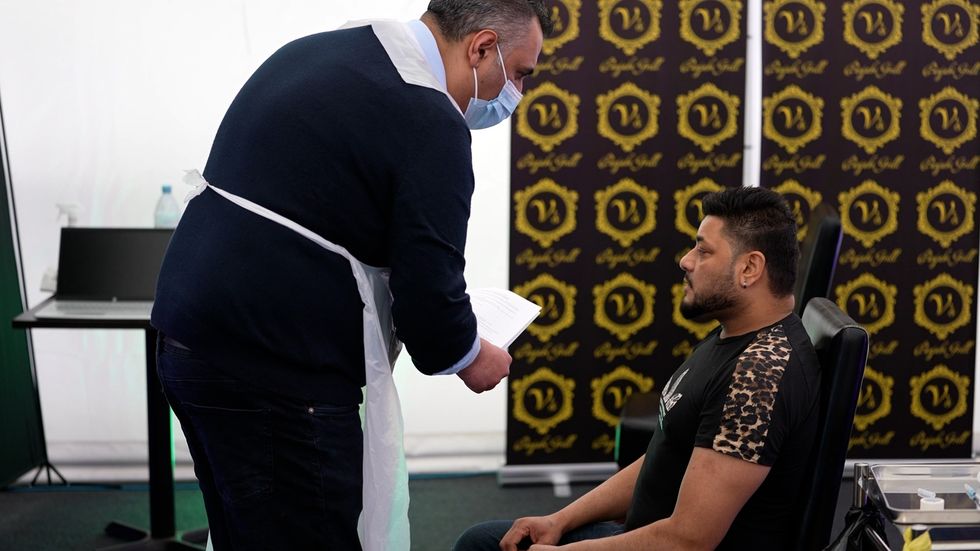Rav Chopra, vaccinating a customer in a marquee set with his brother Raj