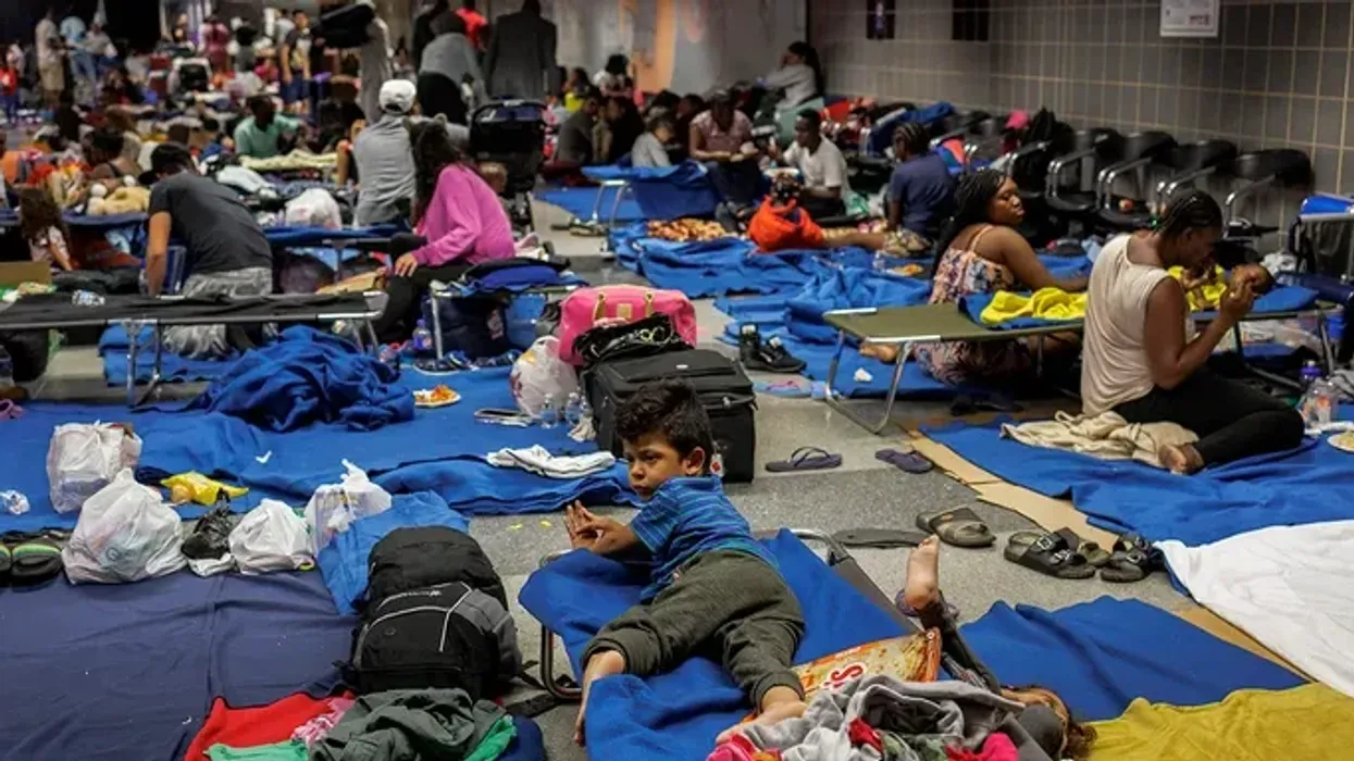 Recently arrived migrants sit on cots and the floor of a makeshift shelter operated by the city at O'Hare International Airport on Aug 31, 2023