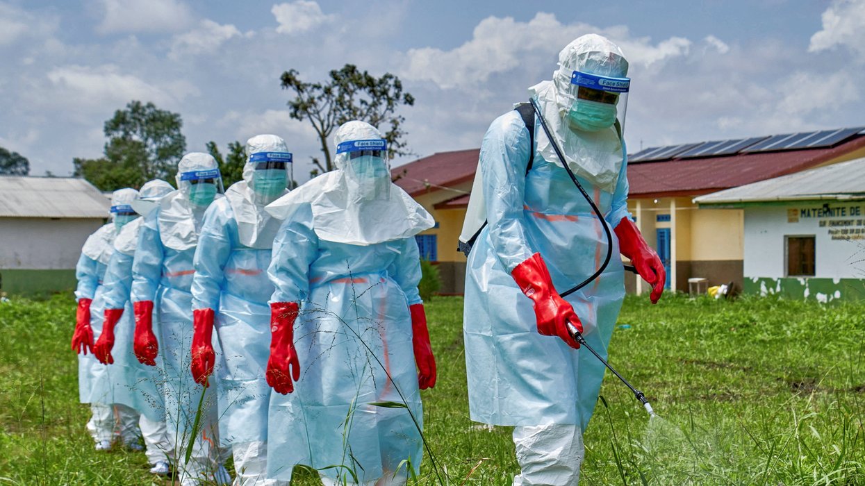 Red Cross workers walk in a formation as they disinfect Rwampara general hospital