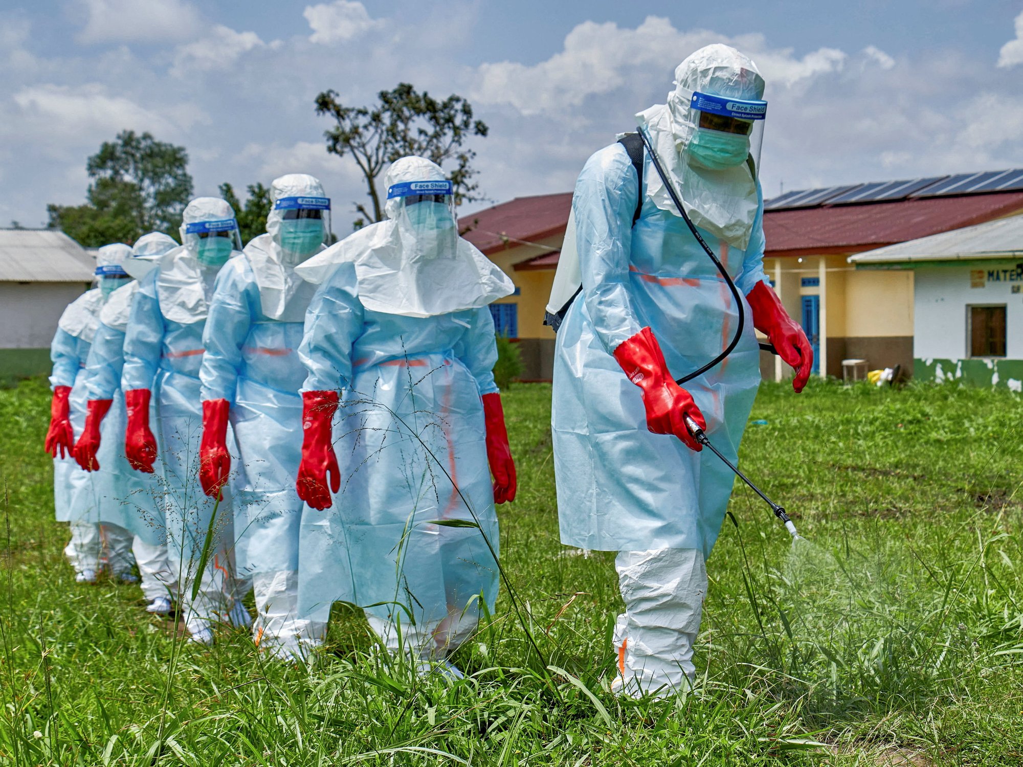 Red Cross workers walk in a formation as they disinfect Rwampara general hospital