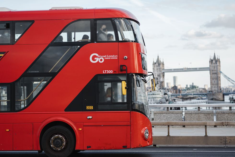 Red London bus on bridge in front of Tower Bridge