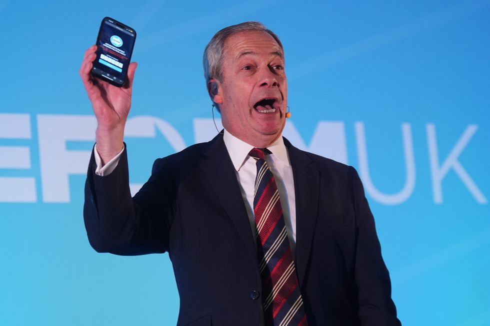 Reform UK leader Nigel Farage holding a phone displaying the number of Reform UK party members whilst speaking during the Reform UK East of England conference at Chelmsford City Racecourse