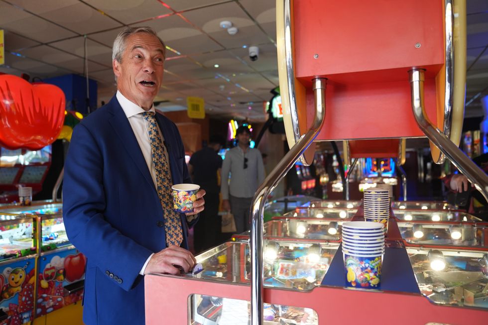 Reform UK leader Nigel Farage playing a 2p machine in Clacton-on-Sea, Essex, while on the General Election campaign trail