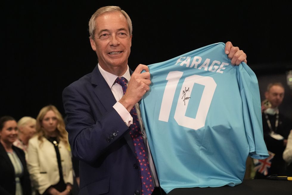 Reform UK leader Nigel Farage signing a football shirt during the party's annual conference at the National Exhibition Centre in Birmingham