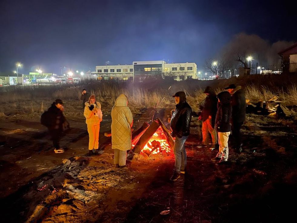 Refugees stand around a fire to keep warm in Polish village Medyka where it's -6C