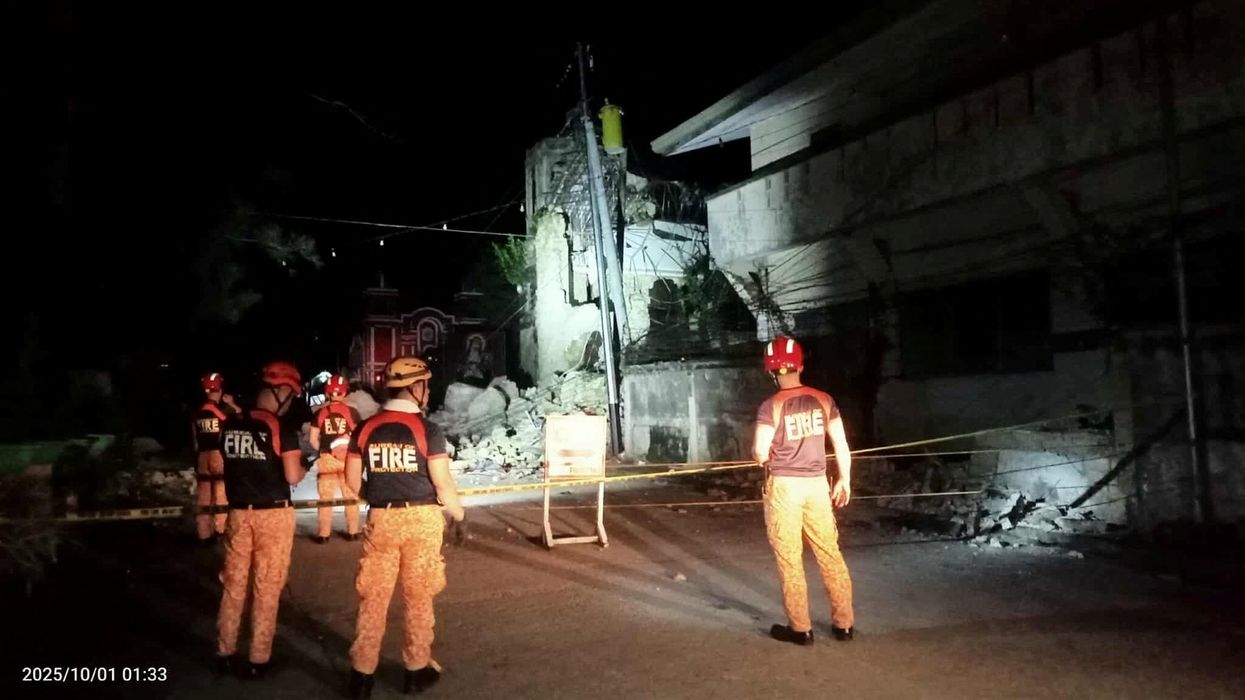 Rescue personnel stand in front of a damaged structure following a 6.9-magnitude earthquake, in Daanbantayan, Cebu province