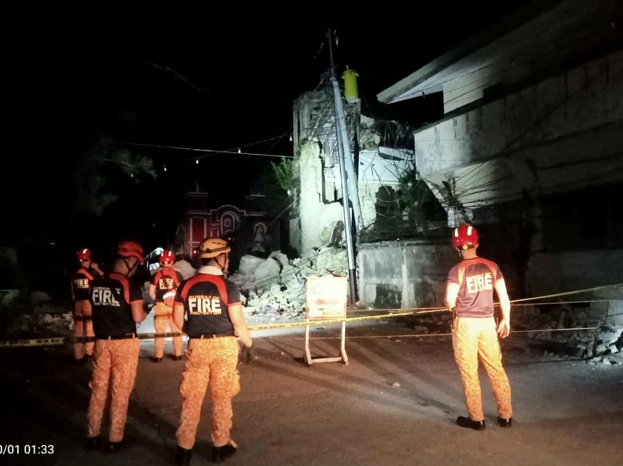 Rescue personnel stand in front of a damaged structure following a 6.9-magnitude earthquake, in Daanbantayan, Cebu province