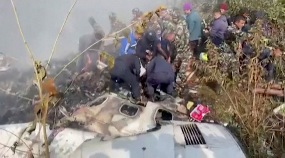 Rescuers work at the site of a plane crash in Pokhara, Nepal