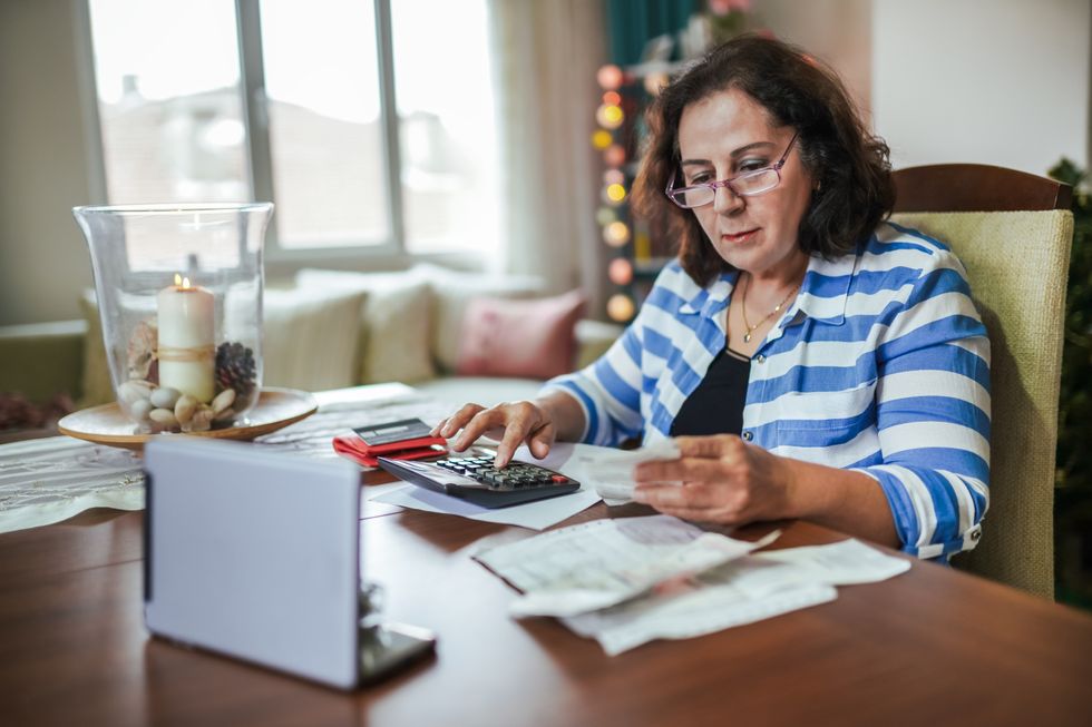 Retired woman looks at receipts with calculator