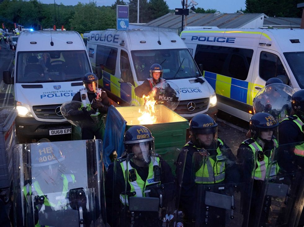 Riot police facing down a flaming dumpster