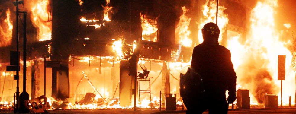 Riot police look on as fire rages through a building in Tottenham, north London