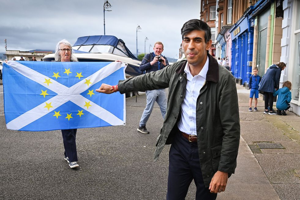 Rishi Sunak in Scotland with a protester in the background