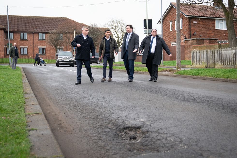 Rishi Sunak walking towards a pothole.