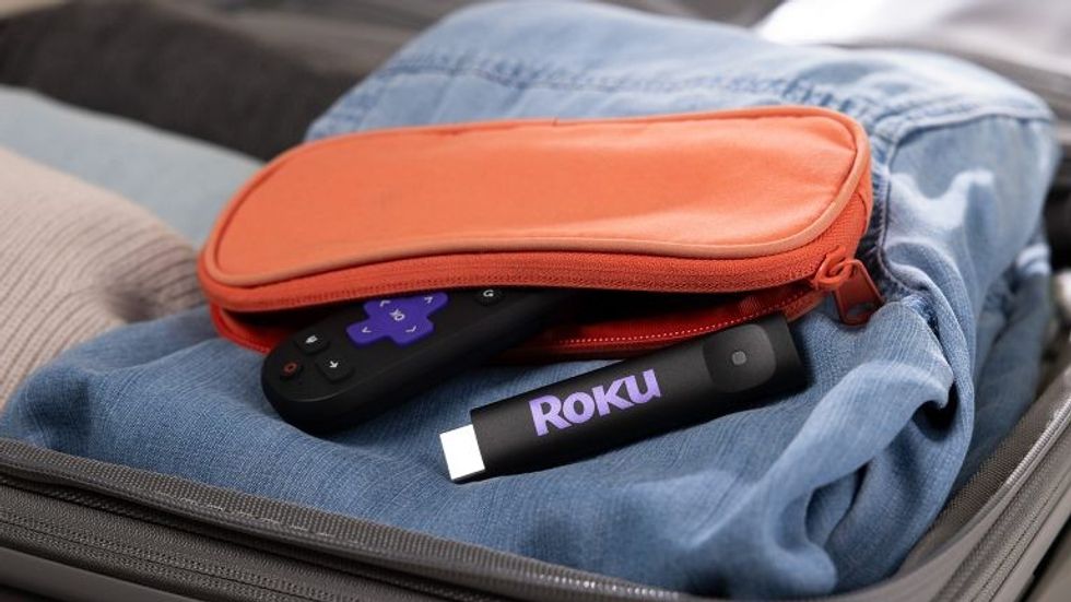 Roku Streaming Stick pictured in an overnight travel bag being packed with clothes