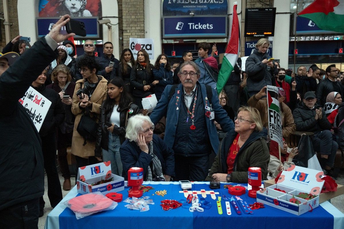 Royal British Legion poppy sellers look on as they are surrounded by people staging a sit-in inside Charing Cross train station during a pro-Palestinian demonstration