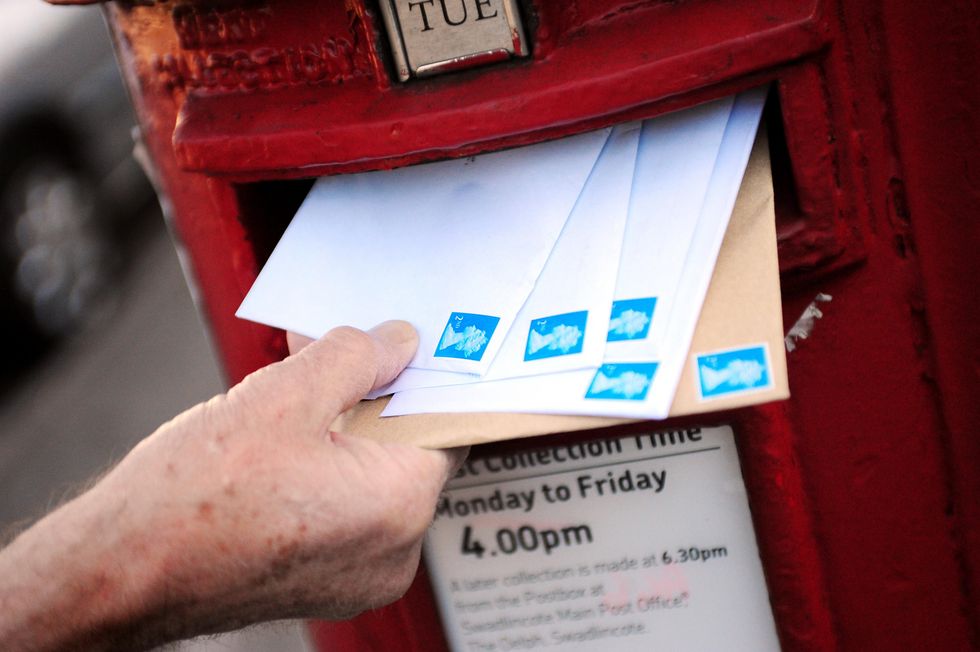 Royal Mail post box and second class stamps on letters being posted