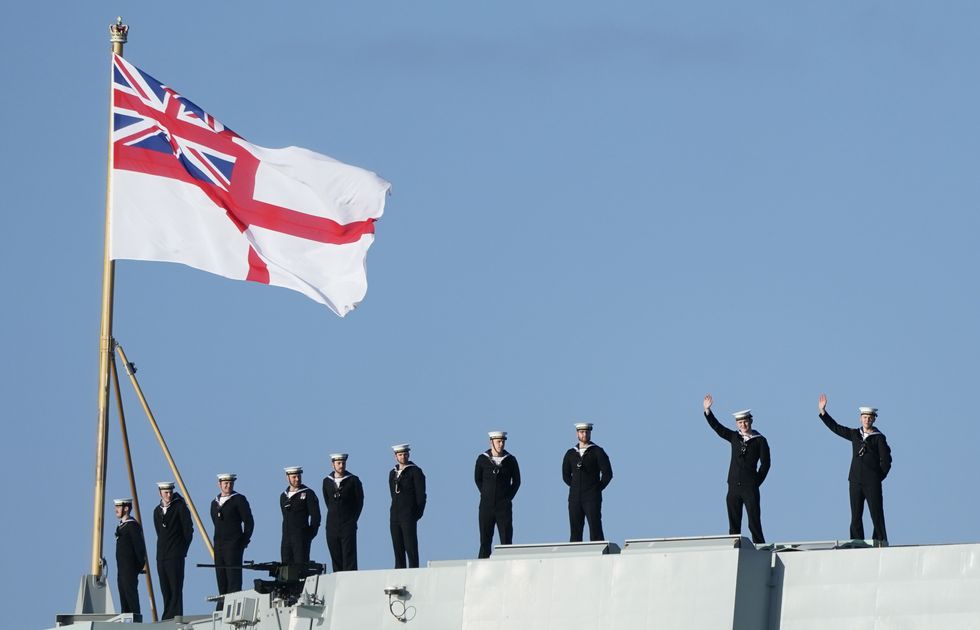 Sailors wave from the stern of the Royal Navy aircraft carrier HMS Prince of Wales