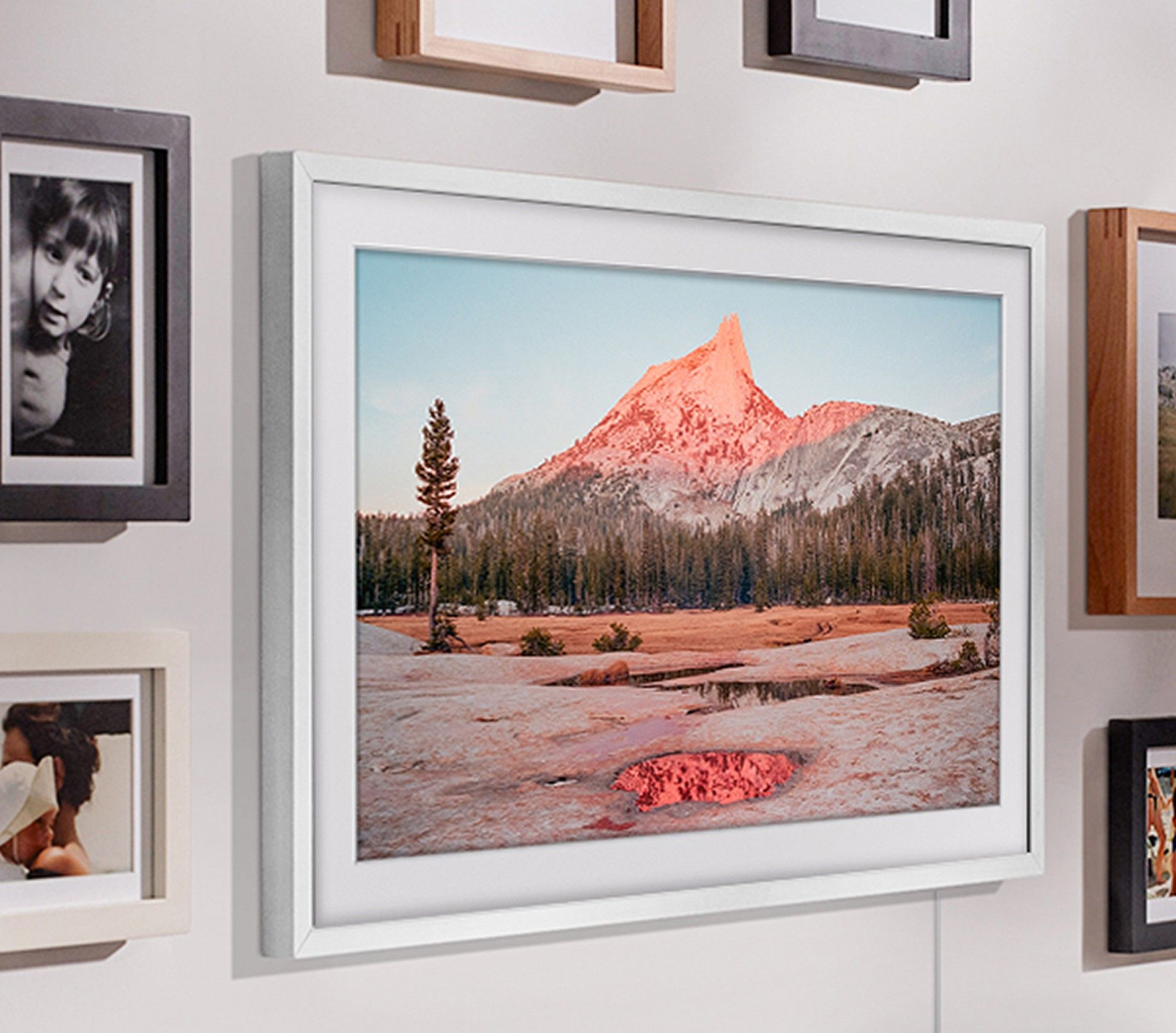 samsung the frame pictured mounted on the wall with artwork a photograph shown on-screen