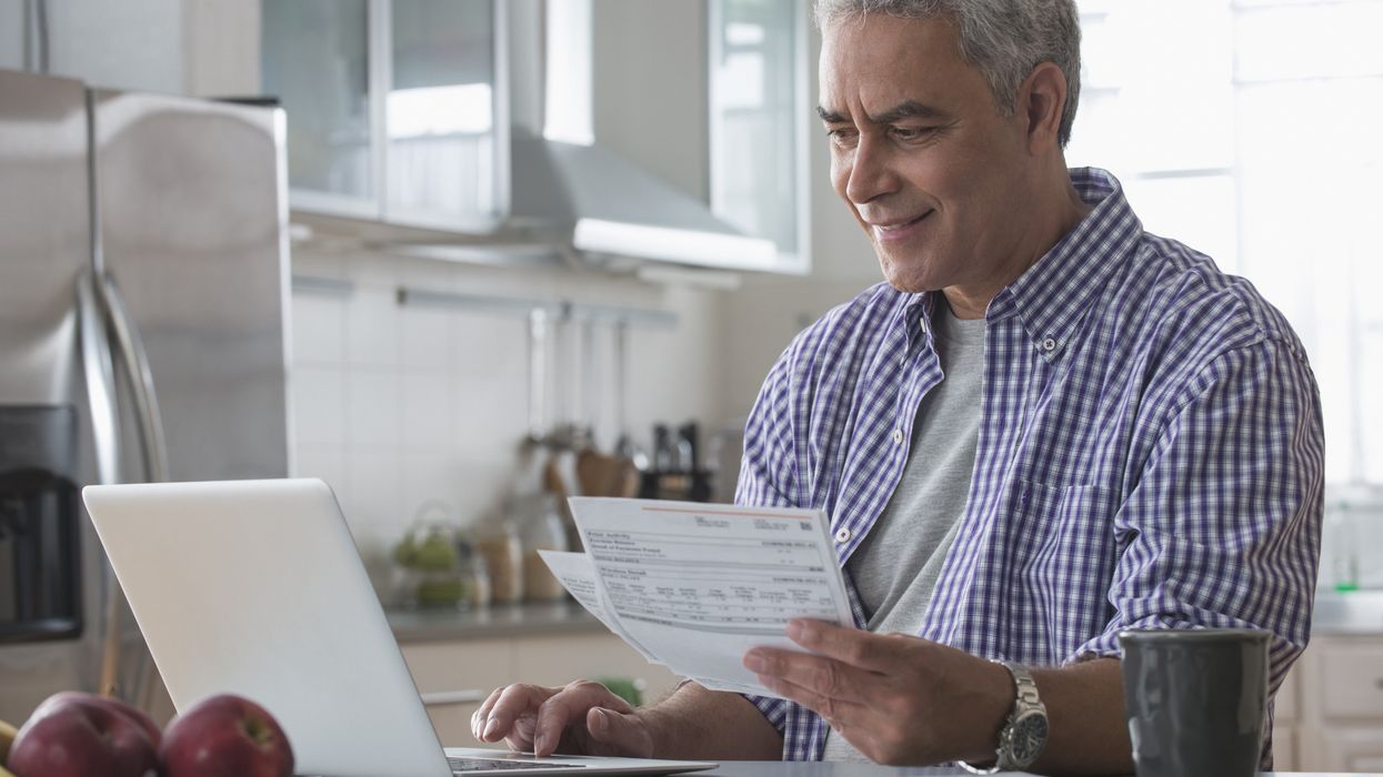 Saver looks at laptop with financial documents in hand