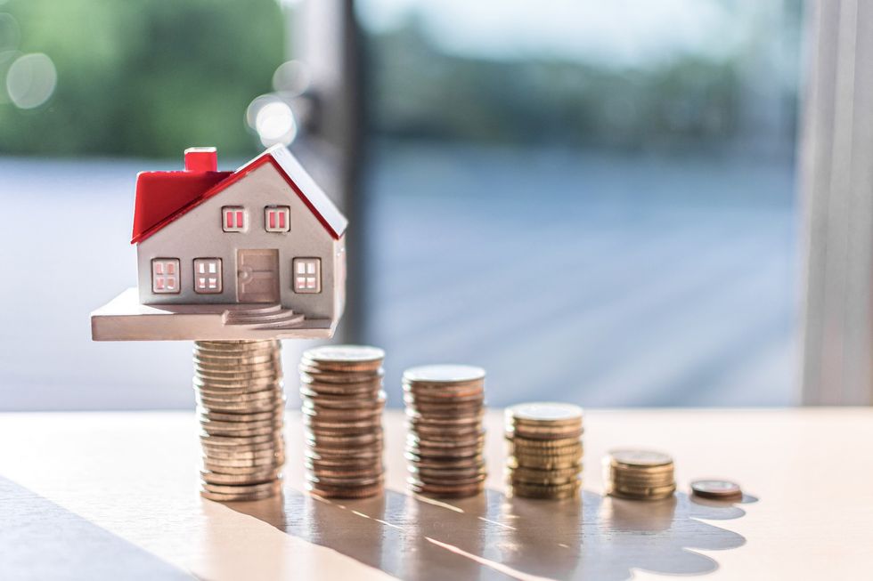 Saving for a house concept \u2013 miniature house with coins