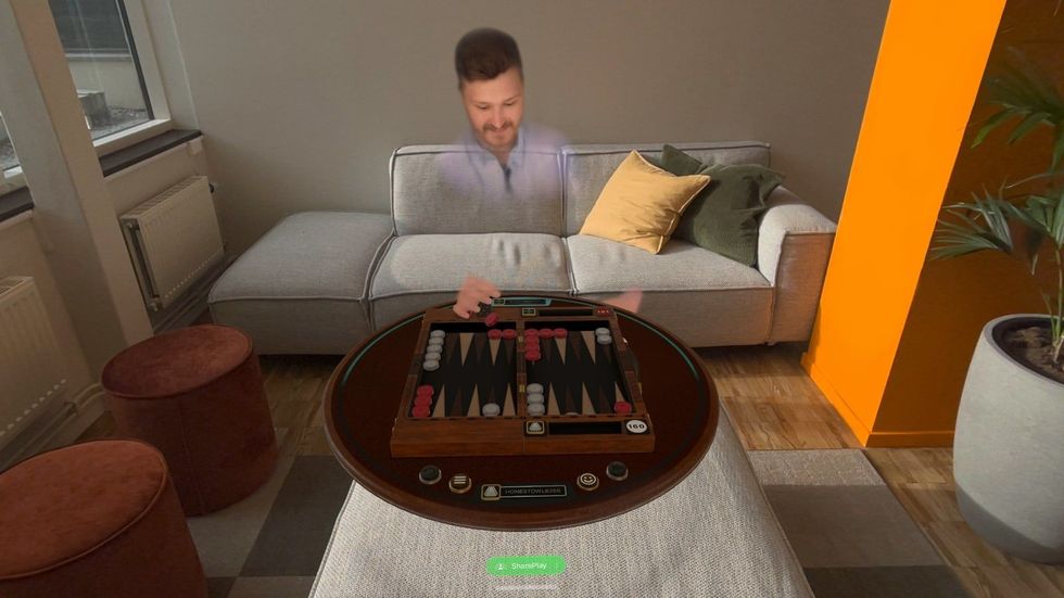 screenshot from game room app showing a persona sitting on the other side of a table playing backgammon