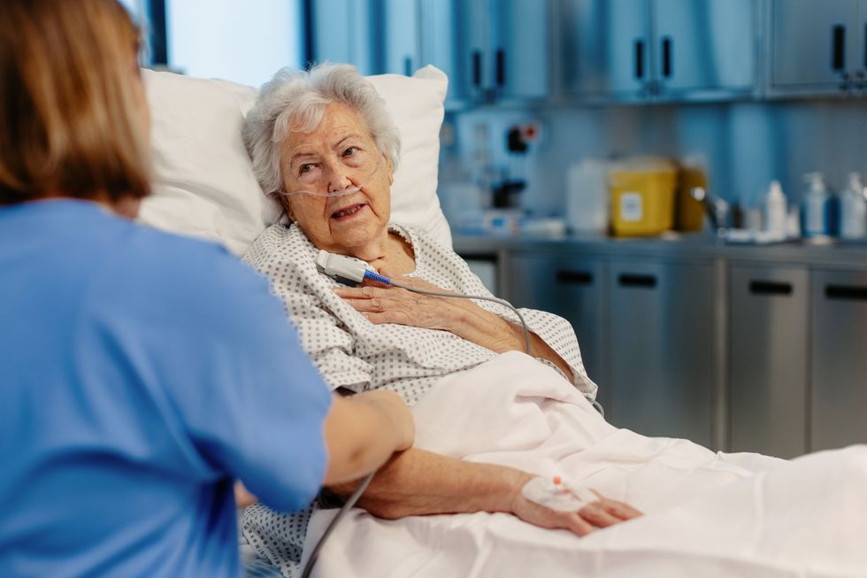 Senior woman in a hospital bed being tended to by a doctor
