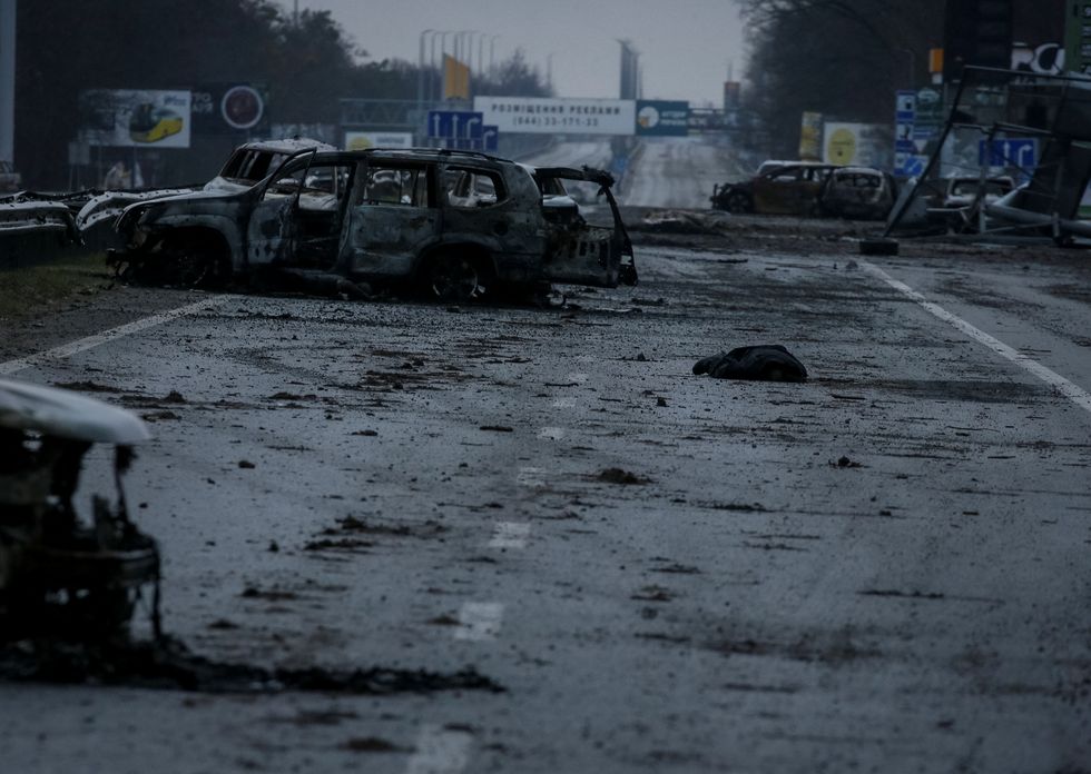 SENSITIVE MATERIAL. THIS IMAGE MAY OFFEND OR DISTURB A body of a civilian, who according to residents was killed by Russian army soldiers, lies near burned cars on the highway, amid Russia's invasion of Ukraine, in the village of Myla, in Kyiv region, Ukraine April 2, 2022. REUTERS/Gleb Garanich