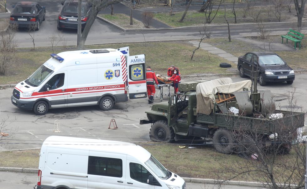 SENSITIVE MATERIAL. THIS IMAGE MAY OFFEND OR DISTURB  Medics transport a person wearing a military uniform into an ambulance near a damaged unidentified military truck at a residential area in Kyiv, Ukraine February 25, 2022. REUTERS/Olga Yakimovich